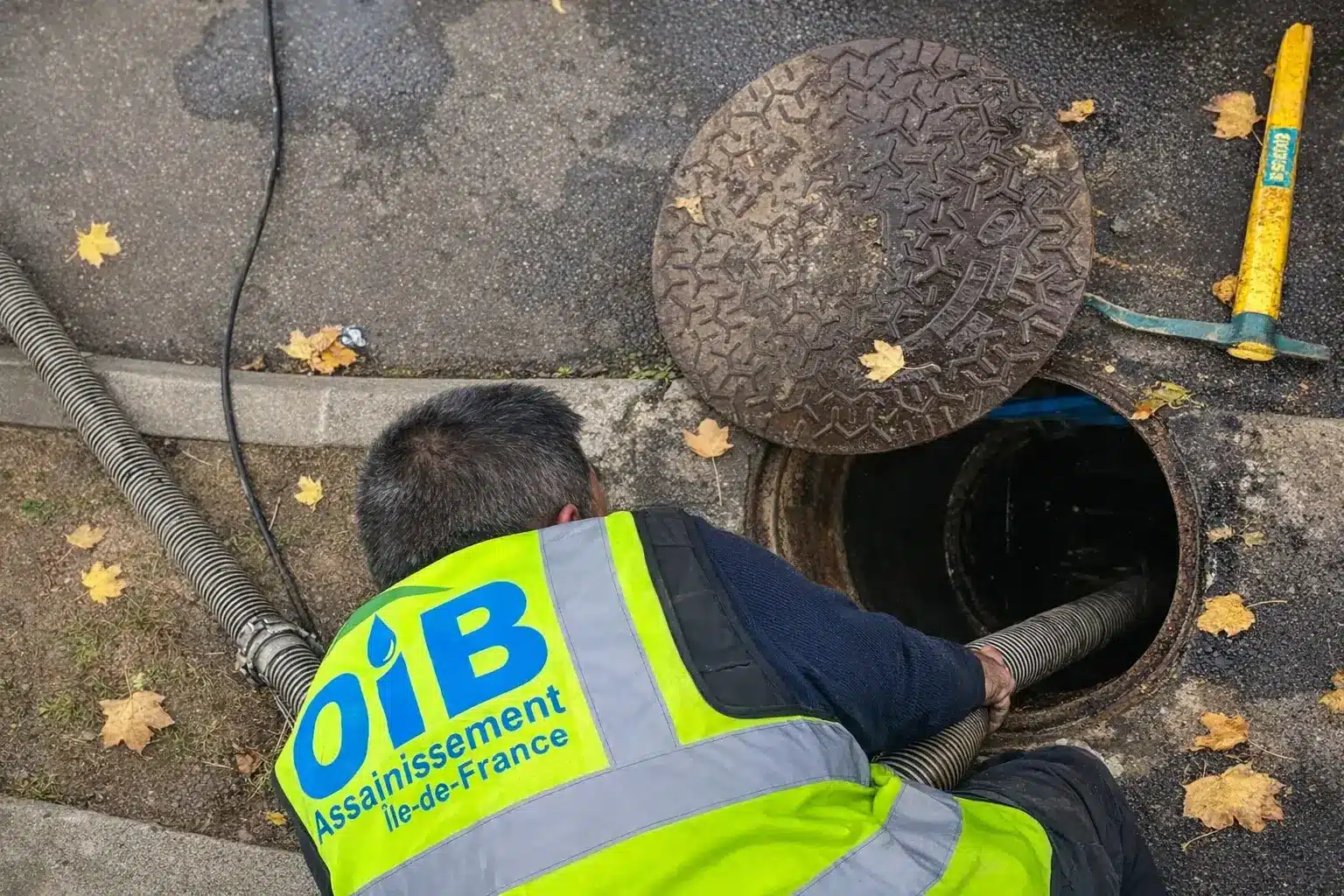 Technicien OIB Assainissement ouvrant un regard et curant une canalisation en Île-de-France
